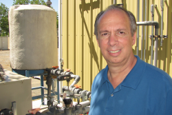 Pictured here is Michael Brambley in front of equipment that supplies chilled water to PNNL Building Diagnostics Laboratory's air handler. The cooled air from an air handler is distributed to terminal boxes, which are the last point for controlling air temperature and flow before distributing it throughout a building zone. In a new control strategy for commercial buildings, the terminal boxes would process the information collected by occupancy sensors to control the air handler's fan speed for energy savings. | Photo courtesy of Kristin Nolan, freelancer.