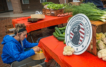 A rainy morning does not stop the Bigg Riggs Farm team member Shaylyn Bohrer from setting up their produce stand at the Old Town Farmers' Market in Alexandria, VA on Saturday, Jun. 27, 2015