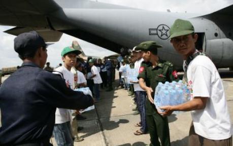 Burma service members form a line to carry water, food, and medical supplies off a C-130 at the Yangon International airport.