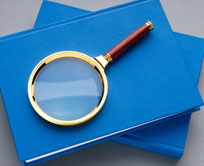 Photo of magnifying glass on top of blue books.  