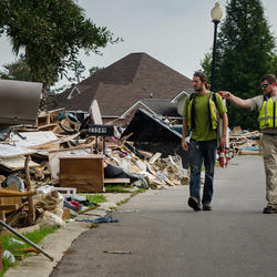 Two men walk by debris along the side of the road