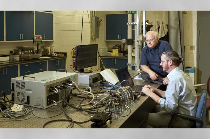 L-R: Roger Kisner, Alexander Melin with the magnetic suspension testbed and its associated electronics and controls.