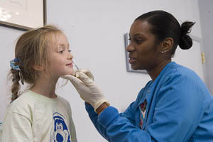 A female nurse/doctor giving the flu mist to a girl.