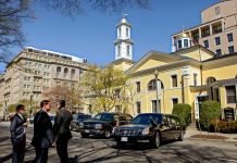 Men and cars in front of yellow church (© AP Images)