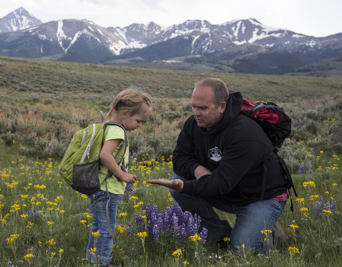 A father and daughter examine flower plants in a field. BLM photo.