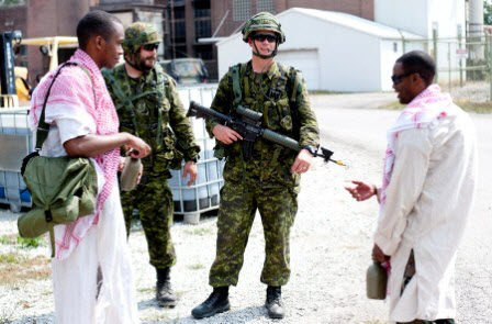 Canadian Soldiers with the 1st Battalion, Royal 22nd Regiment Canadian Infantry, conduct a site visit while wearing 4G LTE cellular technology called Jolted Tactics which allows live video of the engagement to be sent instantly to a command center during Bold Quest 13.2, a combined demonstration going on at the Atterbury-Muscatatuck Complex in southern Indiana with our Bold Quest coalition partners to assess the integration of joint fires, maneuver and cyber in a live/virtual environment and to help enhance combat effectiveness, reduce fratricide and improve situational awareness. Photo by Sgt. 1st Class Brad Staggs/Atterbury-Muscatatuck Public Affairs.