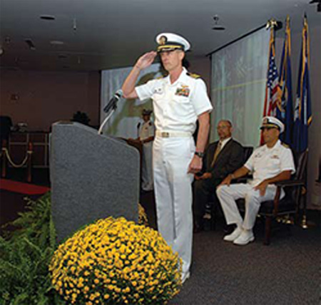 Capt. James C. Cox, former commanding officer of the disestablished SSC Norfolk at the stand up ceremony for SPAWAR Systems Center Atlantic. Cox is now the executive officer for the newly commissioned SSC Atlantic organization. SSC Atlantic Commanding Officer Capt. Bruce Urbon and SSC Atlantic Technical Director Phillip Charles are shown seated behind Cox.