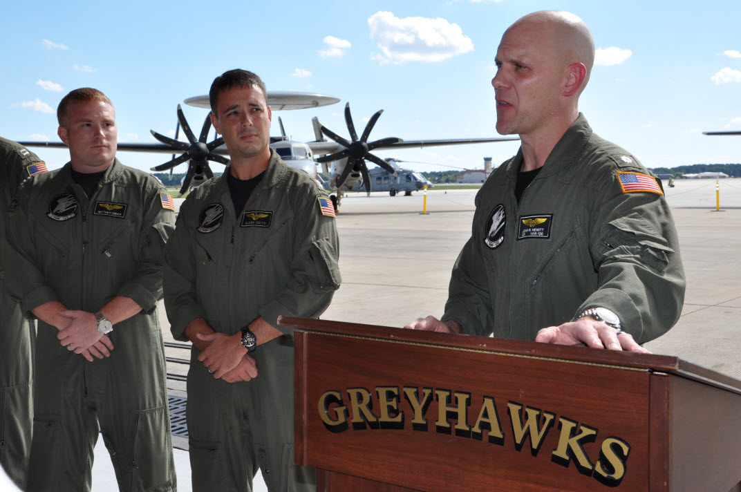 From left, Lt. Matthew Orner and Lt. Glenn Smith, pilots with the Carrier Airborne Early Warning Squadron (VAW)-120 Greyhawks, look on Oct. 16, 2014 as Cmdr. John W. Hewitt, commanding officer, welcomes members of the press to the VAW-120 hangar at Naval Station Norfolk, Va. U.S. Navy photo/Chris Basham. 