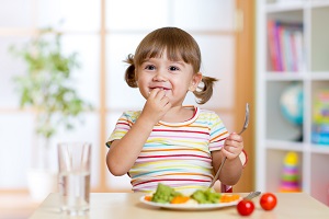 	A young girl eating vegetables