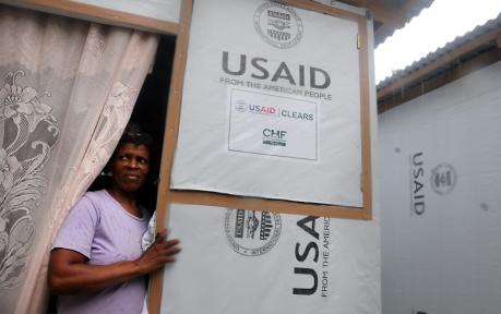 Chantal Chancy keeps dry from the rain inside her family’s USAID-funded transitional shelter in Mayotte, Port-au-Prince, Haiti.
