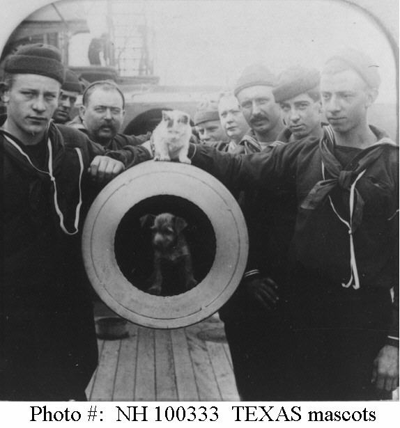 USS Texas (1895-1911) - Crewmen pose with mascot dog and cat at the muzzle of one of the ship's 12"/35 guns. The original photograph was copyrighted in 1900 by R.Y. Young, and published as a lightly color-tinted semi- transparency stereograph card by the American Stereoscopic Co., New York. Courtesy of Commander Donald J. Robinson, USN (Ret), 1982. (Photo courtesy of Naval History and Heritage Command)
