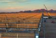 Installing a concentrating solar power system in Gila Bend, Arizona. The curved  mirrors are tilted toward the sun, focusing sunlight on tubes that run the length of the mirrors. The reflected sunlight heats a fluid flowing through the tubes. The hot fluid then is used to boil water in a conventional steam-turbine generator to produce electricity. | Photo by Dennis Schroeder. 