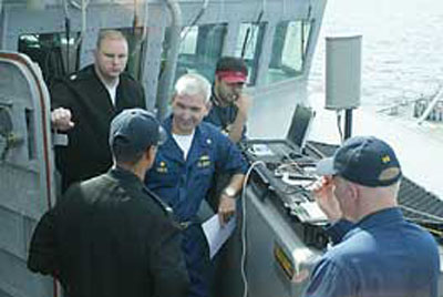 Suhail Khan mans a laptop in the background as USS Carney Commanding Officer Cmdr. Patrick Shea is all smiles after receiving a photo via the wireless link. The wireless link between the interdicted vessel and the host Navy ship reaches up to two nautical miles.