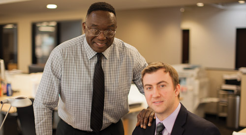 picture of two men in an office, smiling