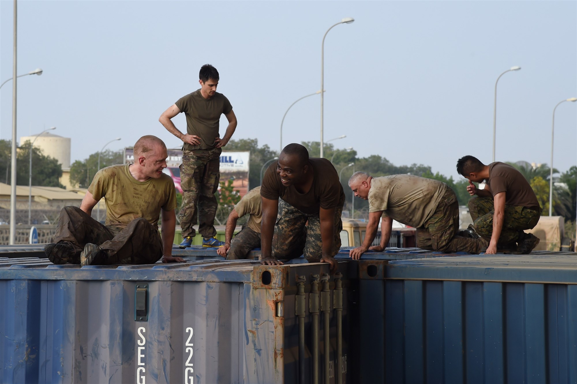 Service members from Combined Joint Task Force-Horn of Africa Civil Affairs climb over obstacles during a mud run hosted by the French military, Nov. 6, 2016, in Djibouti, Djibouti. The event allowed coalition forces from French, Japanese, and American teams to interact and build camaraderie while navigating a five kilometer course. The French 5th Marine Regiment team took first place. (U.S. Air Force photo by Staff Sgt. Penny Snoozy)