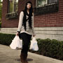 Photo shows a woman walking down the street carrying plastic bags.