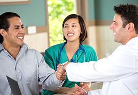 Doctor and patient shaking hands while a nurse looks on