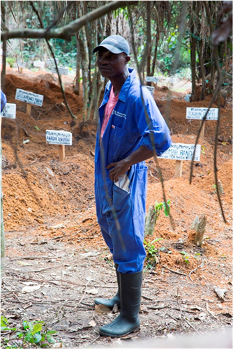 A burial worker stands near the graves of Ebola victims located nearby an active Ebola treatment unit in Suakoko, Liberia, Nov. 22, 2014. United Assistance is a Department of Defense operation to provide command and control, logistics, training and engineering support to U.S. Agency for International Development-led efforts to contain the Ebola virus outbreak in West African nations. (U.S. Army Photo by Sgt. 1st Class Brien Vorhees,/ Released)