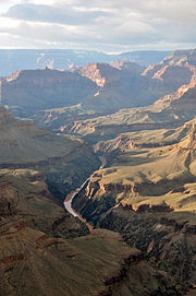 A narrow river flows through a narrow gorge flanked by high rocky bluffs