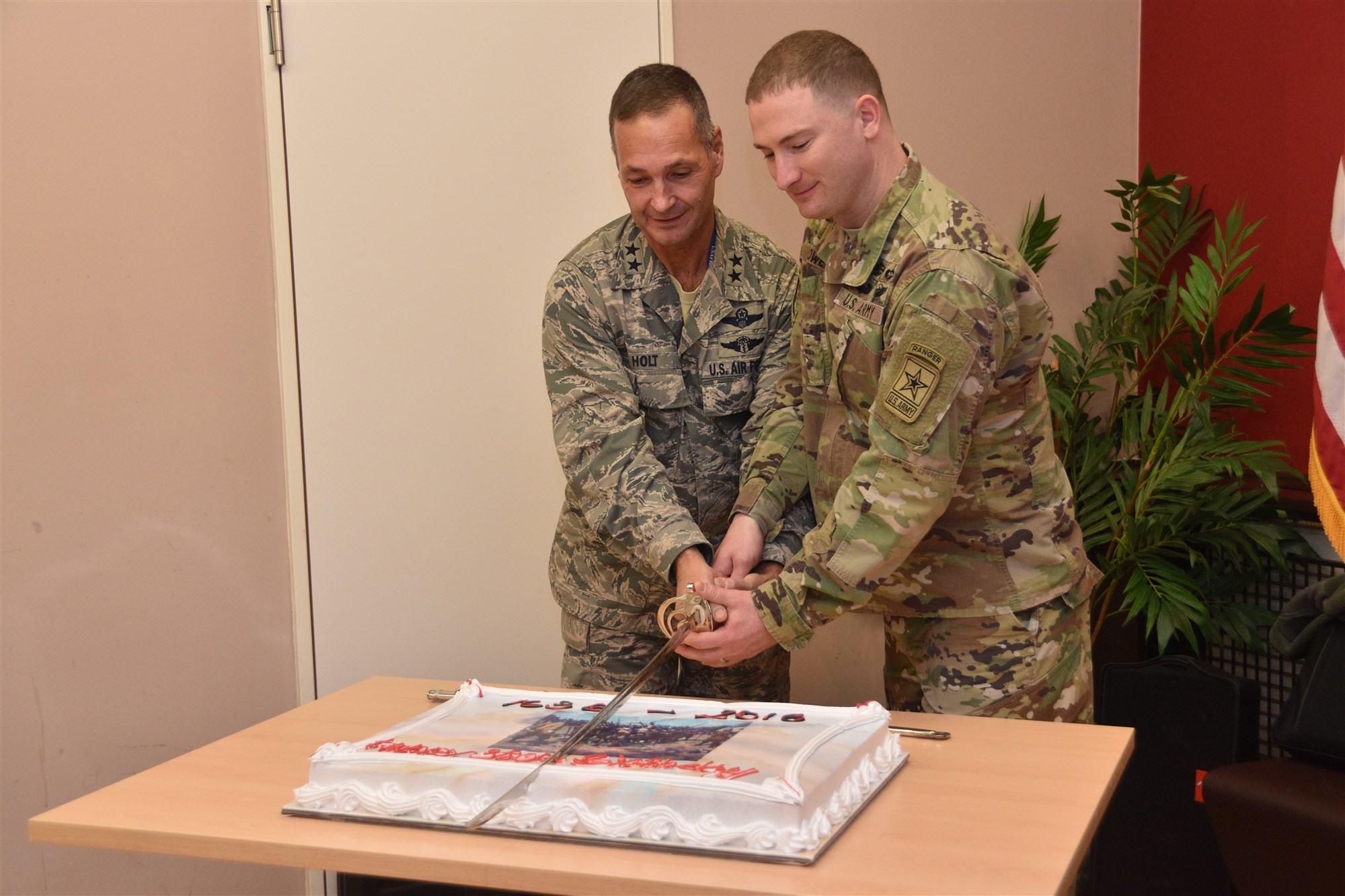 Oldest, Maj. Gen. Worthe Holt, Jr, (left) and youngest, Staff Sgt. Brian Powers, Guardsmen cut the cake. AFRICOM and EUCOM Guardsmen, family and friends celebrated the National Guard's 380th Birthday at an event hosted by Maj. Gen. Holt, Dec. 9, 2016, U.S. Army Garrison Stuttgart, GE. (Photo by Brenda Law, U.S. Africa Command Public Affairs/Released)