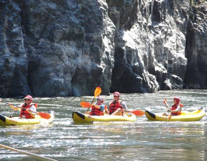 A photo of 3 yellow kayaks floating down the Snake River