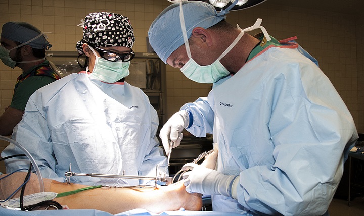 Army Capt. Marina Rodriguez (right), a third year resident with William Beaumont Army Medical Center’s Orthopaedic Residency Program, assists Army Lt. Col. Justin Orr, orthopaedic residency program director, during a total ankle replacement on a beneficiary. (U.S. Army photo by Marcy Sanchez)