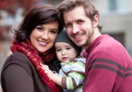 Young Couple Smiles with Baby in Between