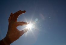 Hand appearing to hold sun between thumb and index finger. (© Design Pics via AP)