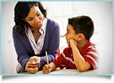 A teacher helps a young boy with his class work. 