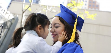 Smiling Mother in graduation gown holding Daughter
