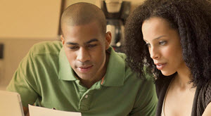 a couple looking at a computer and paperwork