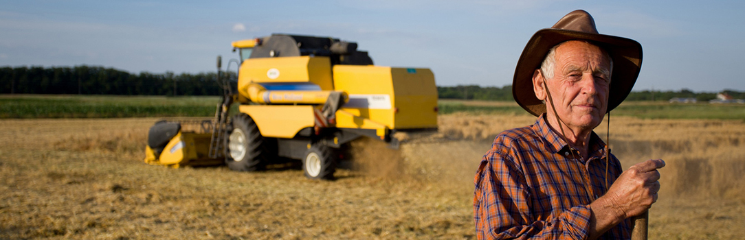 Photo of a farmer in his field, with combine in the background