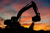An active backhoe working on site as the sunsets.