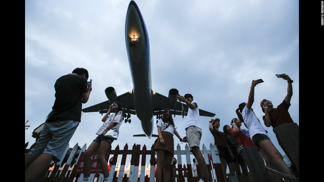 People take photos of an approaching passenger plane in Taipei, Taiwan, on Wednesday, September 6.