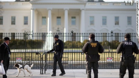 A U.S. Secret Service K-9 team works along the second, temporary fence on the north side of the White House March 18, 2015, in Washington.