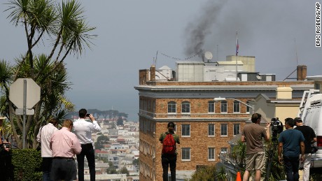 People stop to watch black smoke coming from the roof of the Consulate-General of Russia Friday, Sept. 1, 2017, in San Francisco. The San Francisco Fire Department says acrid, black smoke seen pouring from a chimney at the Russian consulate in San Francisco was apparently from a fire burning in a fireplace. The smoke was seen billowing from the consulate building a day after the Trump administration ordered its closure. (AP Photo/Eric Risberg)
