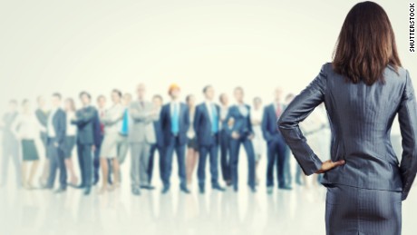 Powerful businesswoman standing with back with business team at background. 