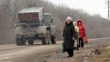 Refugees from Debaltseve are escaping the battle zone on foot while Grad missile systems are heading to the front on February 5, 2015, North of Debalteve, Donbass Oblast, Ukraine. Fighting continues between Ukrainian forces and pro-Russian separatists in and around the important rail ray hub of Debalteve. The humanitarian situation in the town has become catastrophic as thousands have fled, while many more are trapped in the heavily shelled town. Locals each day try to flee the battle zone using cars, trucks or buses driven by volunteers making the round trip multiple times a day.