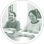 two smiling people sitting at a table with open books