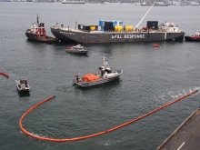 Pollution boom surrounding several small vessels. 