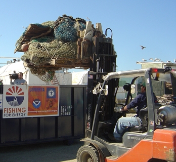 A man in lifting nets out of Fishing for Energy bin with a tractor crane. 