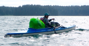 A volunteer in a kayak with a bag of debris.