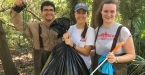 Project participants display collected debris from One Mile Creek, including Mardi Gras beads. (Photo Credit: Mobile Baykeeper)