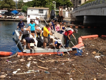 ICC volunteers scoop marine debris out of a trash boom in Honolulu. 