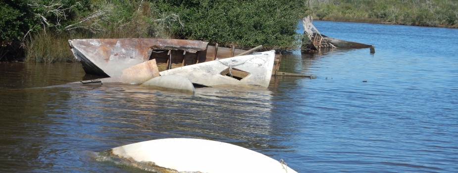 Derelict vessels partially-submerged in water.