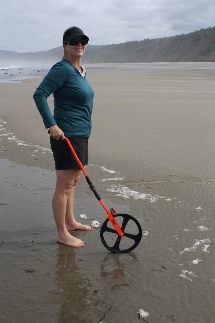 Amy Uhrin standing on a beach with a measuring wheel.