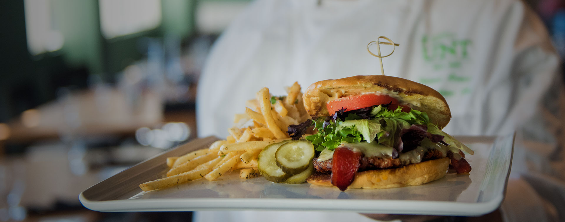 Toasted chicken BLT sandwich with herb-seasoned fries and thick pickle slices.