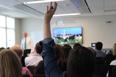 Photo of a classroom full of students with one student holding up a hand