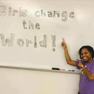 Jasmine Walker at white board that says "Girls change the world!"