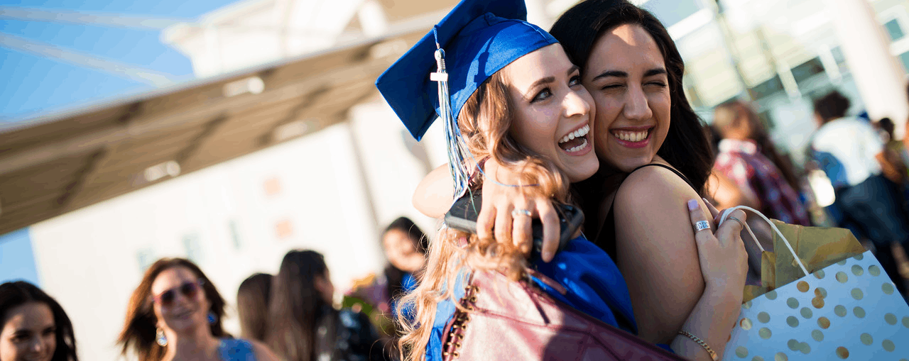 unt dallas graduates celebrate with a hug outside 